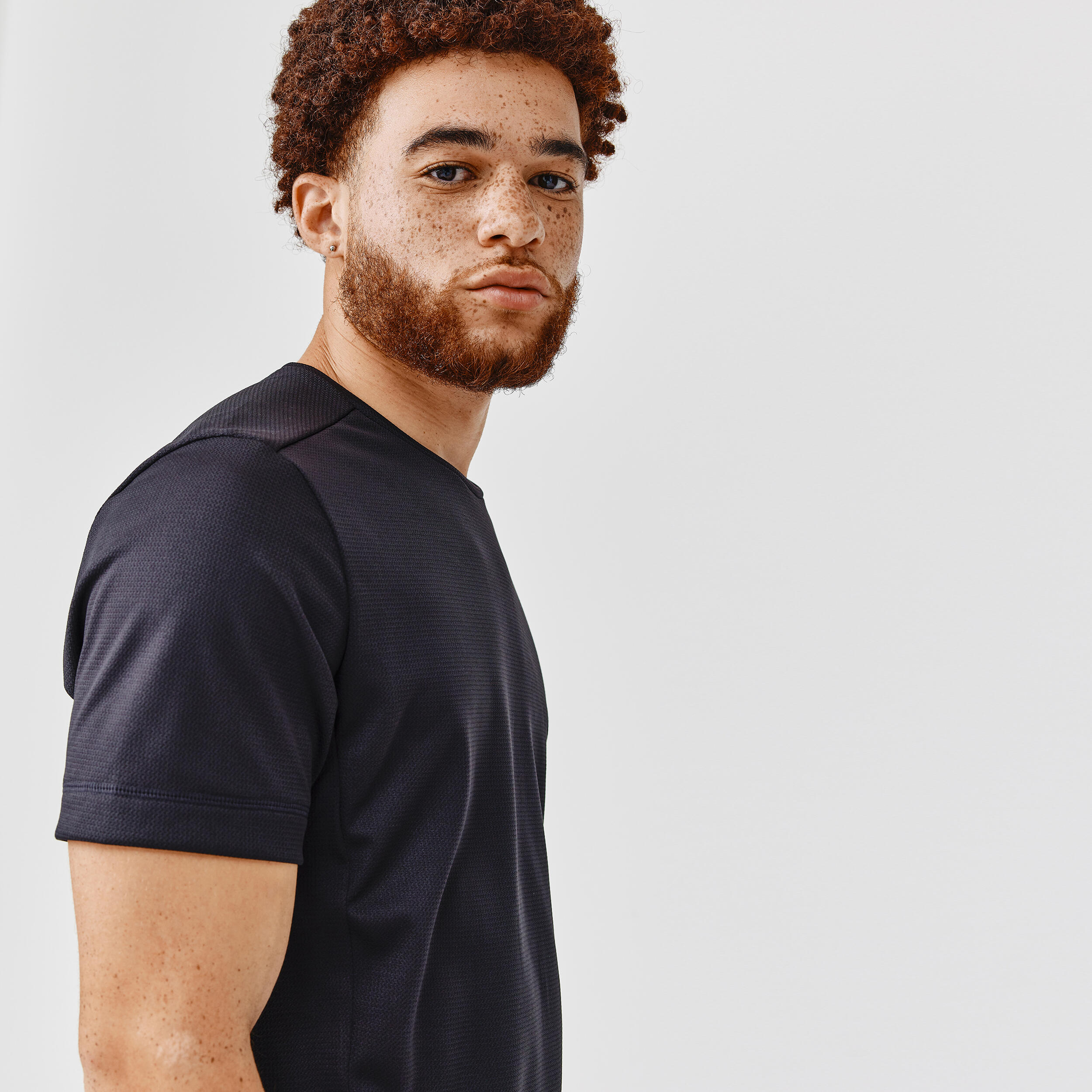 Man wearing a black round neck running tshirt against a light gray background
