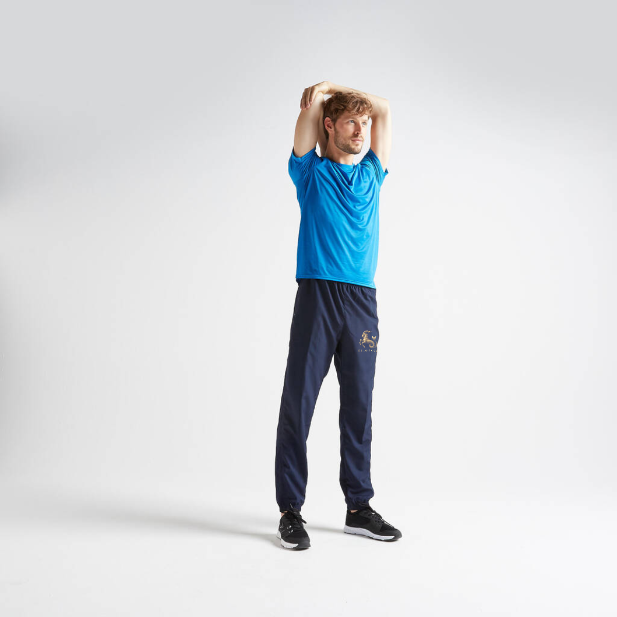 Person wearing a blue shirt and navy tracksuit with a logo on a white background