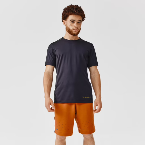 Man wearing a black t-shirt and orange shorts on a light gray background